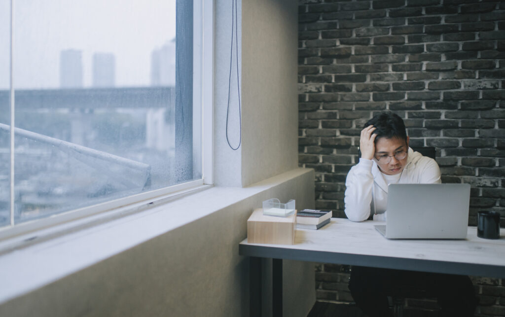 a mid adult man searching online using his laptop looking for job and submitting resume emotional stress malaysian-graduates-job-mismatch-and-unemployment-challenges